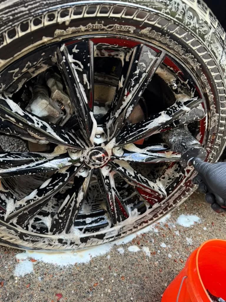 Wheel being deep cleaned with foam and a detailing brush